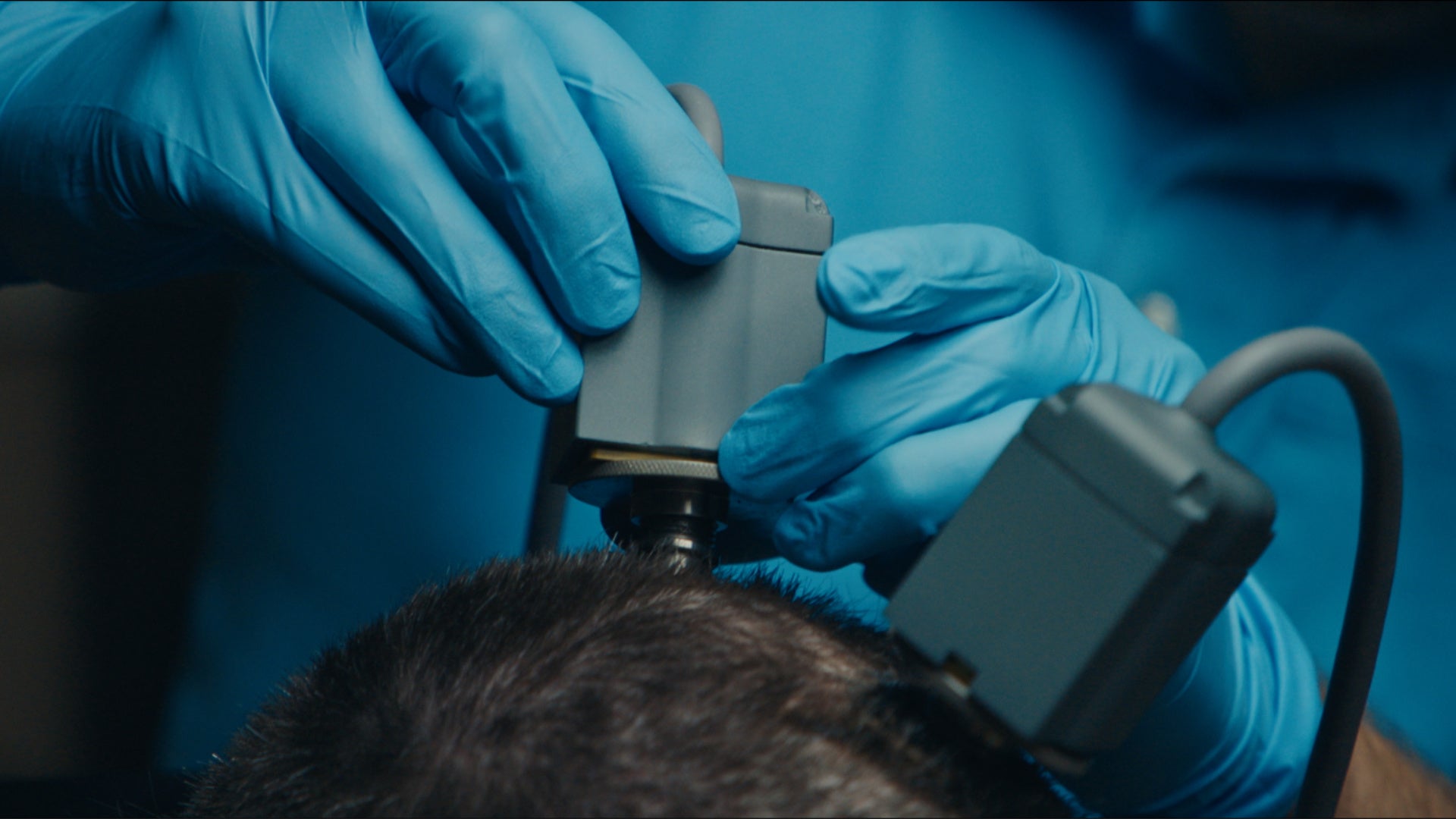 A doctor places a biotechnological device on a patient's head.